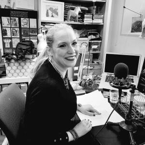 Hanna-Karin sitter framför en mikrofon med ett bokmanus framför sig, i full färd med att läsa in det.